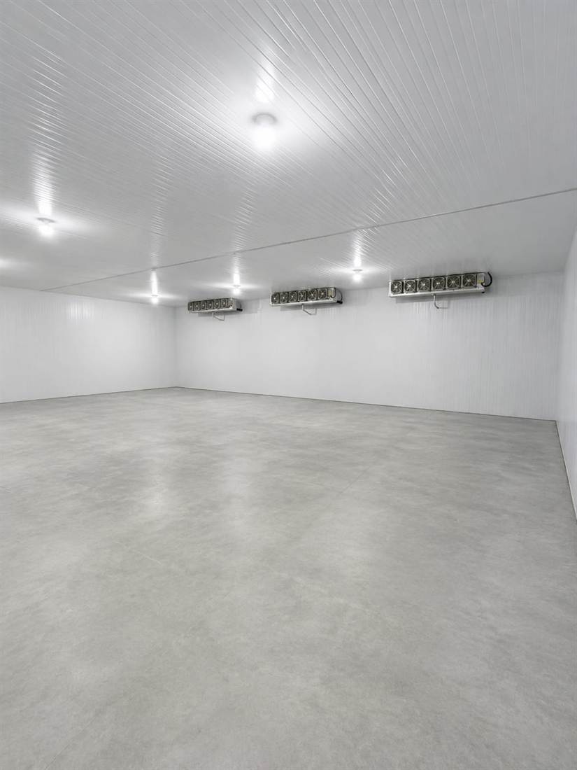 Interior de una nave frigorífica vacía con tres evaporadores en línea sobre la pared y piso de hormigón pulido.