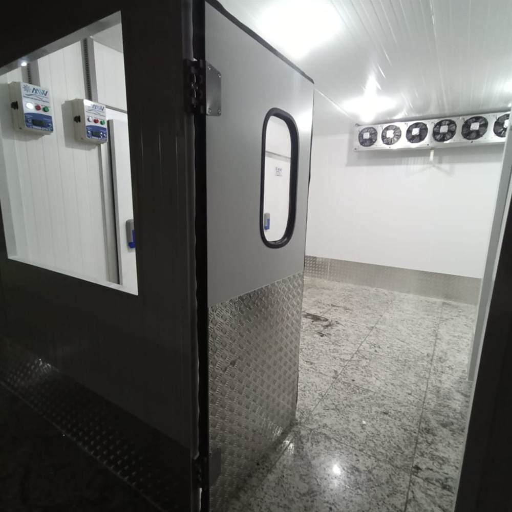 Interior de cámara frigorífica con evaporador de seis ventiladores en el techo y piso de aluminio antideslizante.