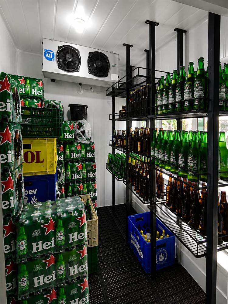 Interior de cámara de bebidas con estibas de cajones y estantería de reposición.